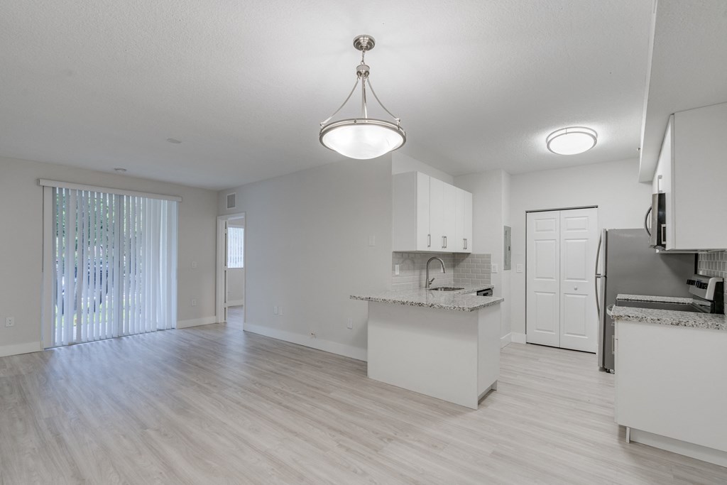 an empty kitchen and living room with a door to a balcony