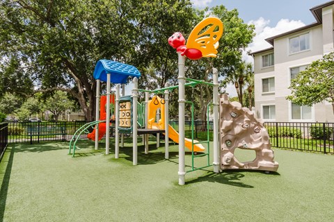 A playground with a slide, climbing frame, and a swing set.
