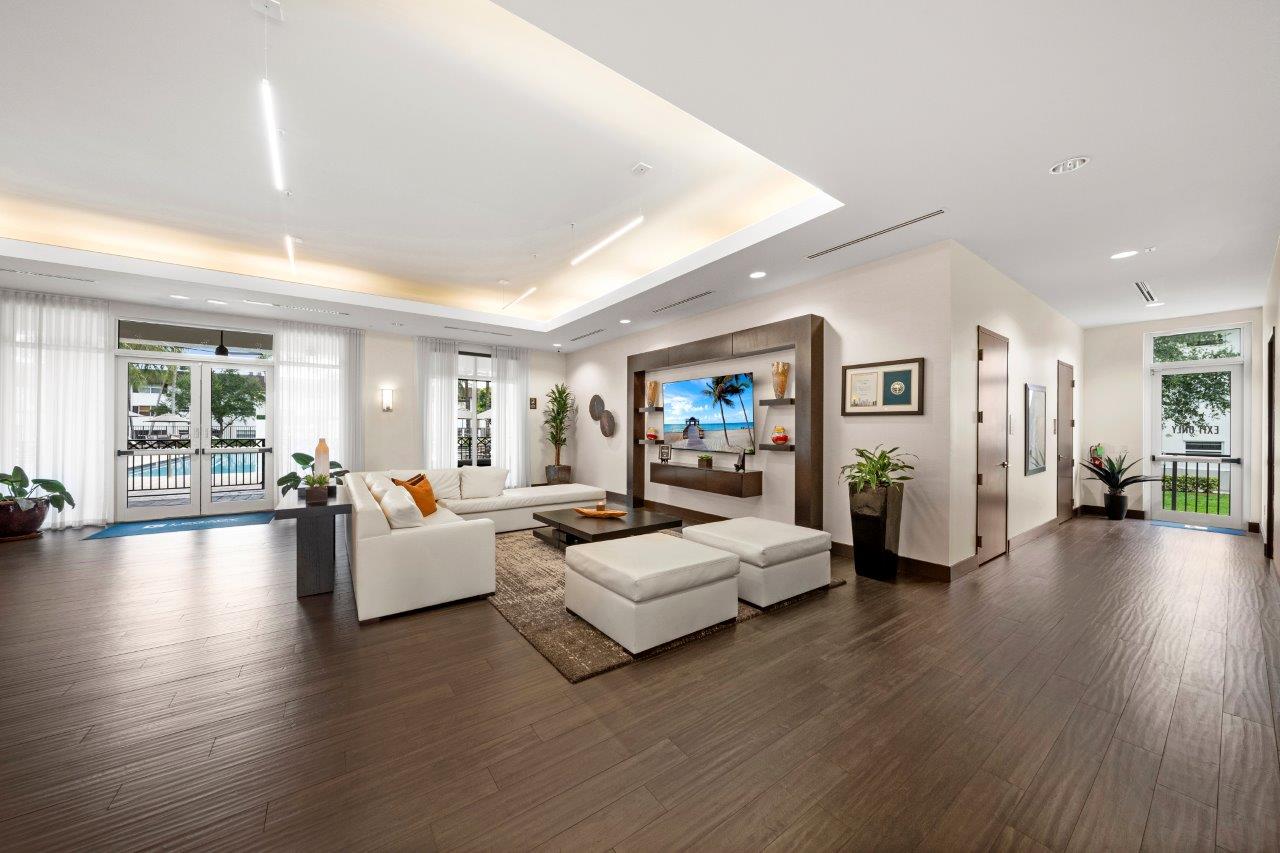 A spacious living room with a white sofa set and a television.