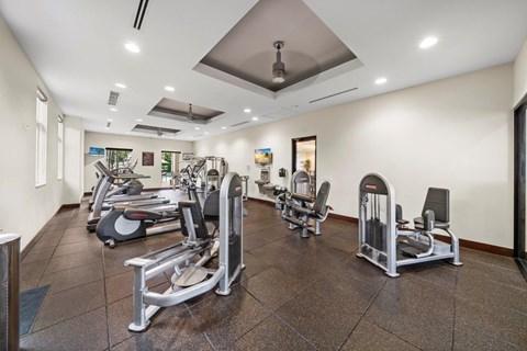 A gym with a variety of equipment including treadmills, weights, and exercise machines.