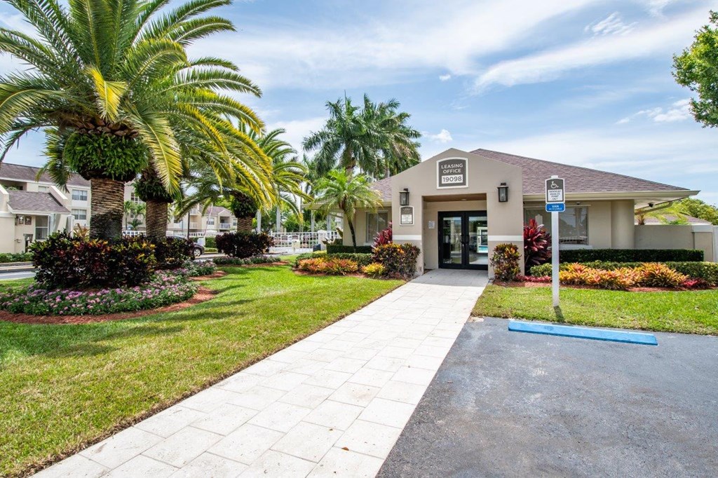 a house with a sidewalk and palm trees in front of it