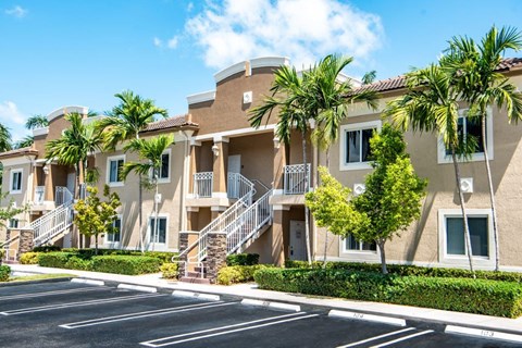 an apartment building with palm trees and a parking lot