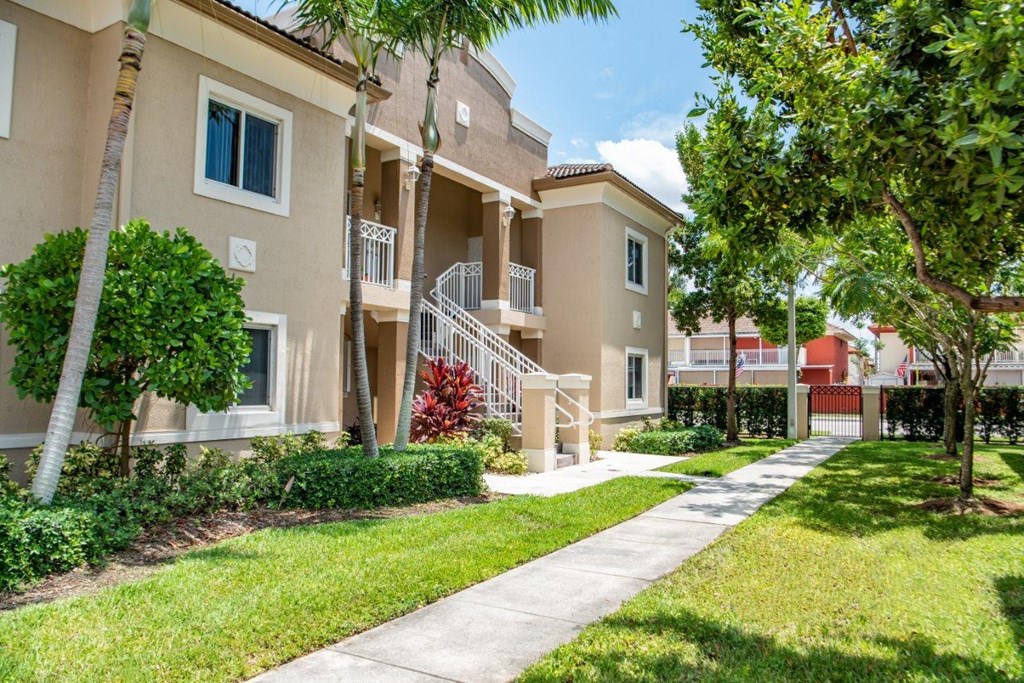 an apartment building with trees and a sidewalk