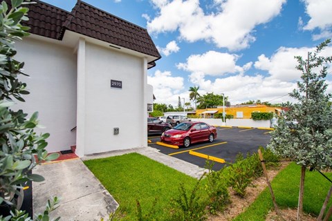 A red car is parked in a yellow-striped parking space.