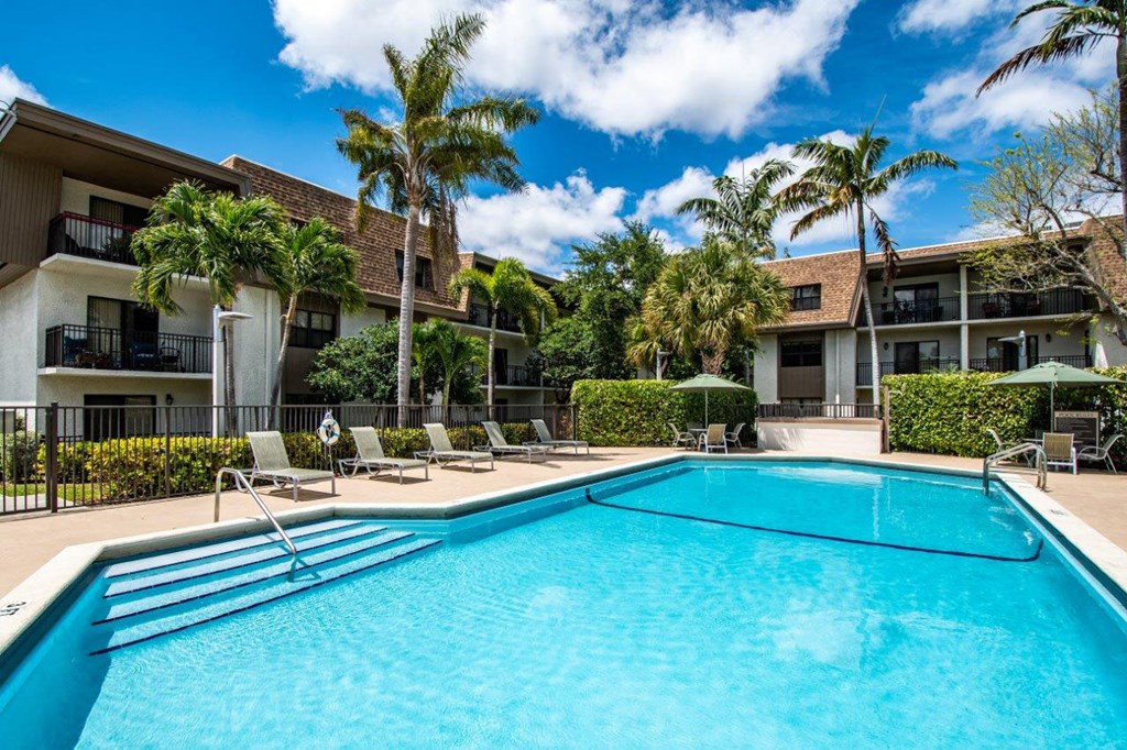 a swimming pool with palm trees in front of an apartment building
