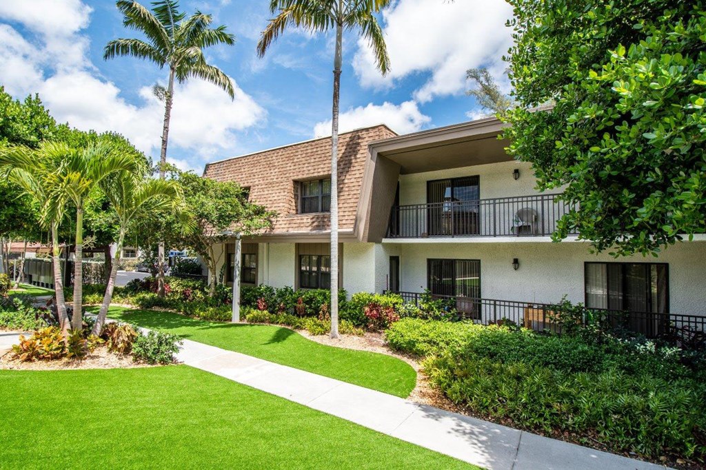 a building with palm trees in front of it and a sidewalk