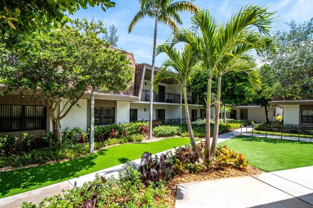 a house with a lawn and palm trees in front of it