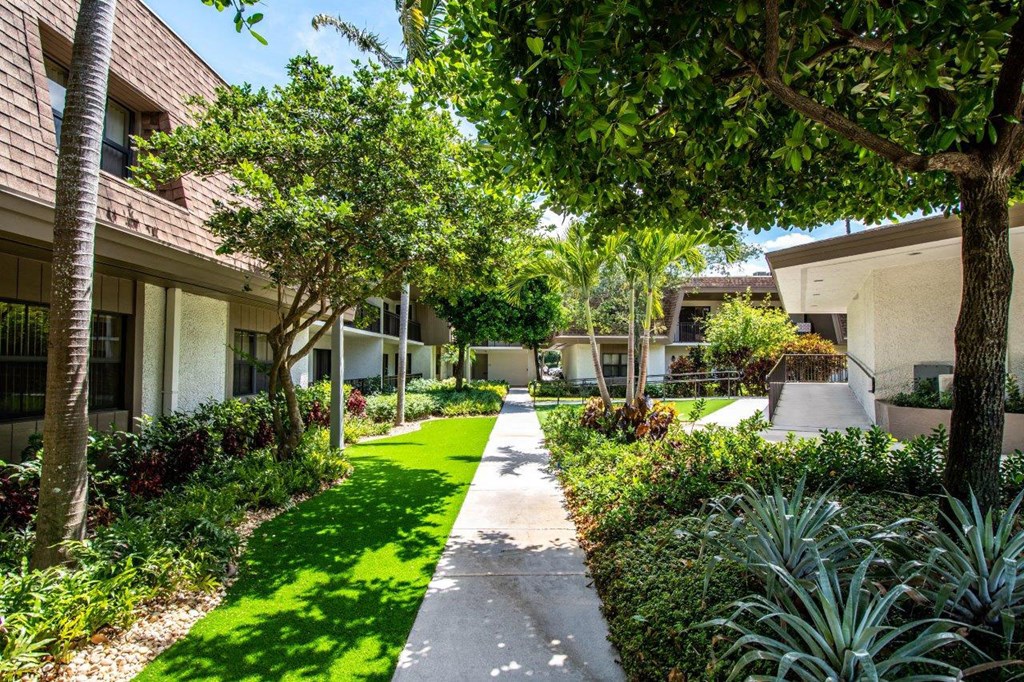 a walkway through a courtyard with trees and grass