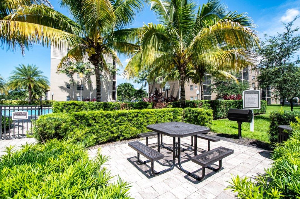 a picnic area with a table and benches in front of a pool