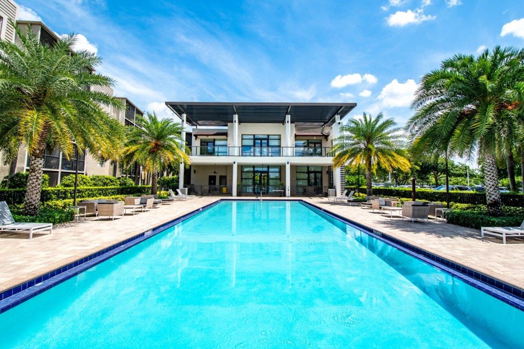 the pool is in front of a large house with palm trees