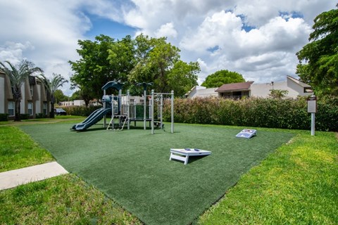 A playground with a green slide and a seesaw.