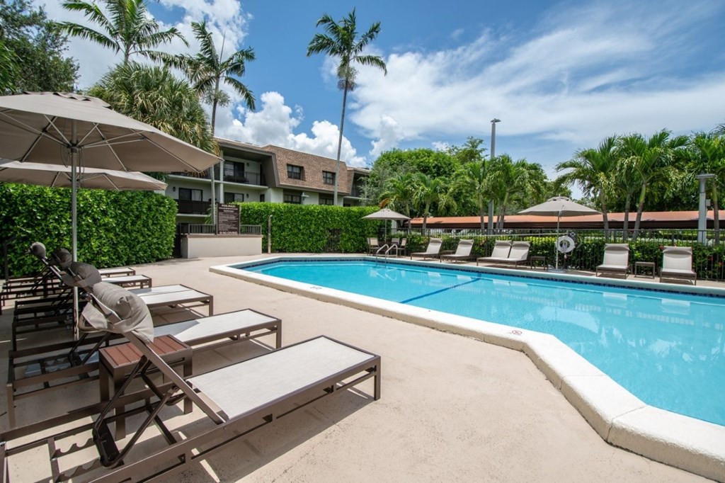 A pool area with sun loungers and umbrellas.