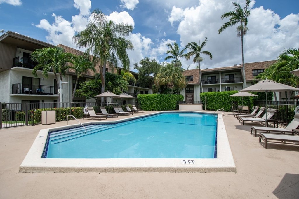 A swimming pool surrounded by lounge chairs and umbrellas.