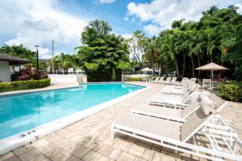 a swimming pool with white chairs and a blue pool