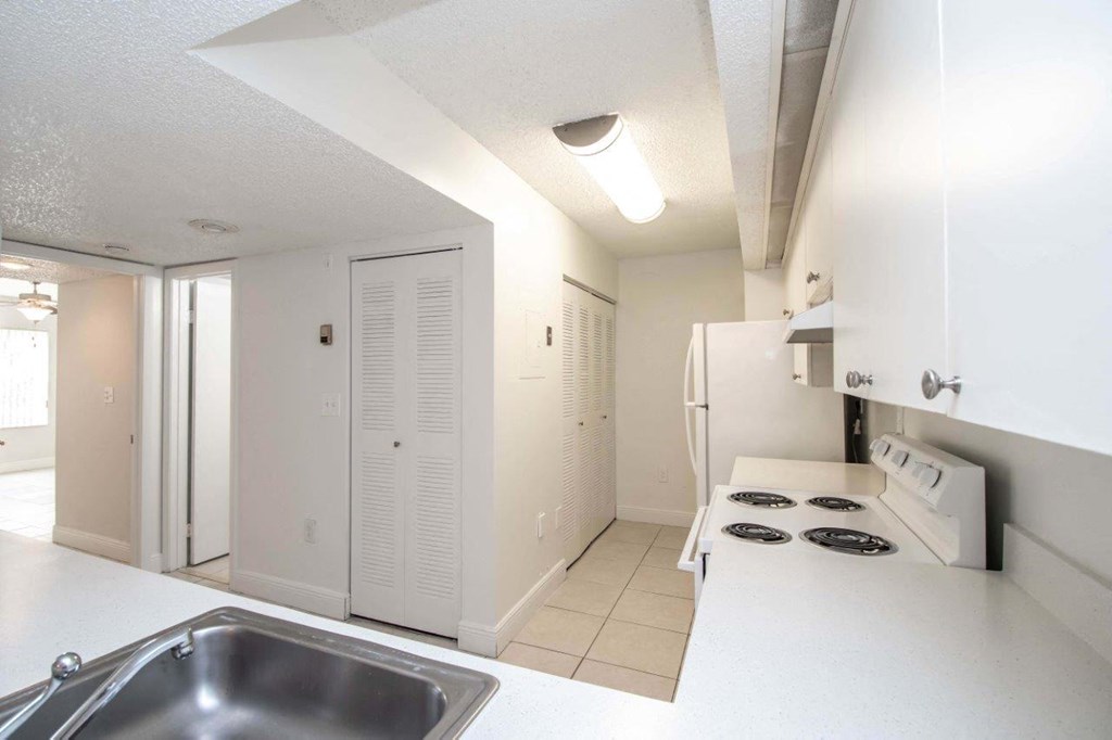a kitchen with white cabinets and a sink and a refrigerator