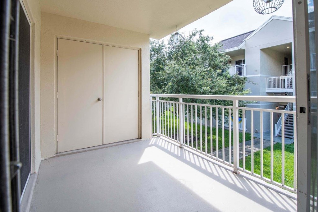 the view from the balcony of an apartment with a door to the yard