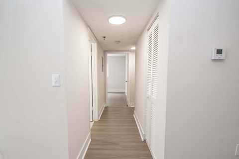 a hallway with white walls and white shutters and a light on the ceiling