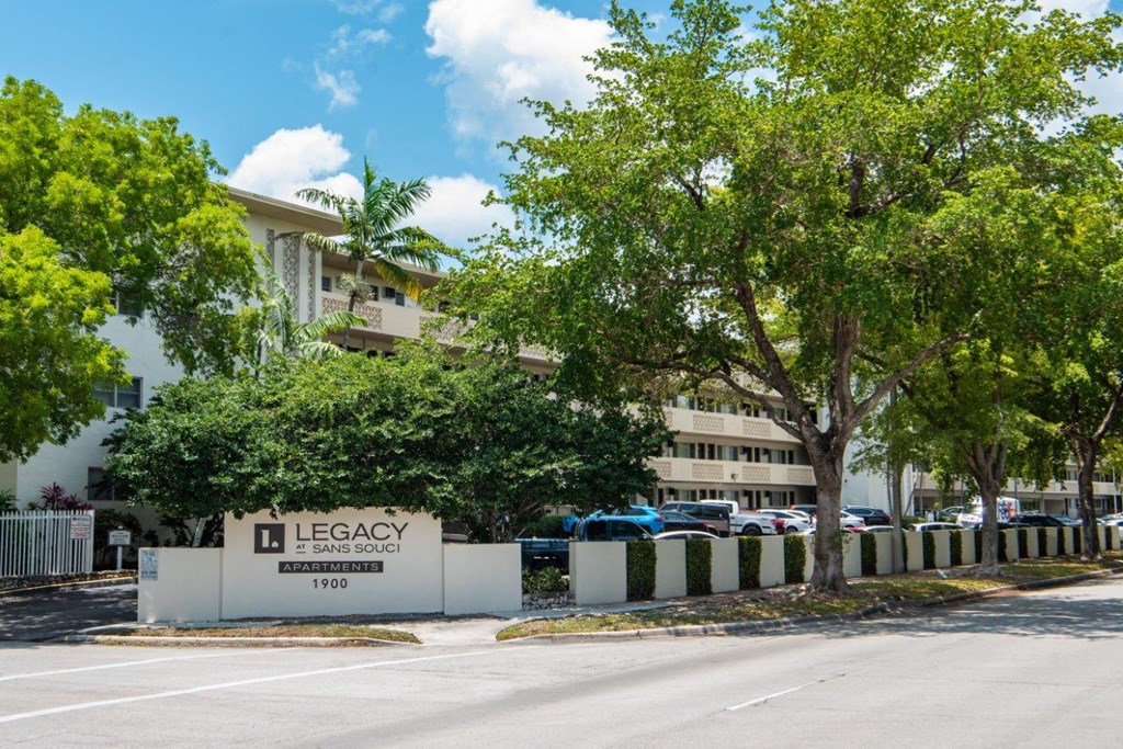 a building with a sign and trees in front of it