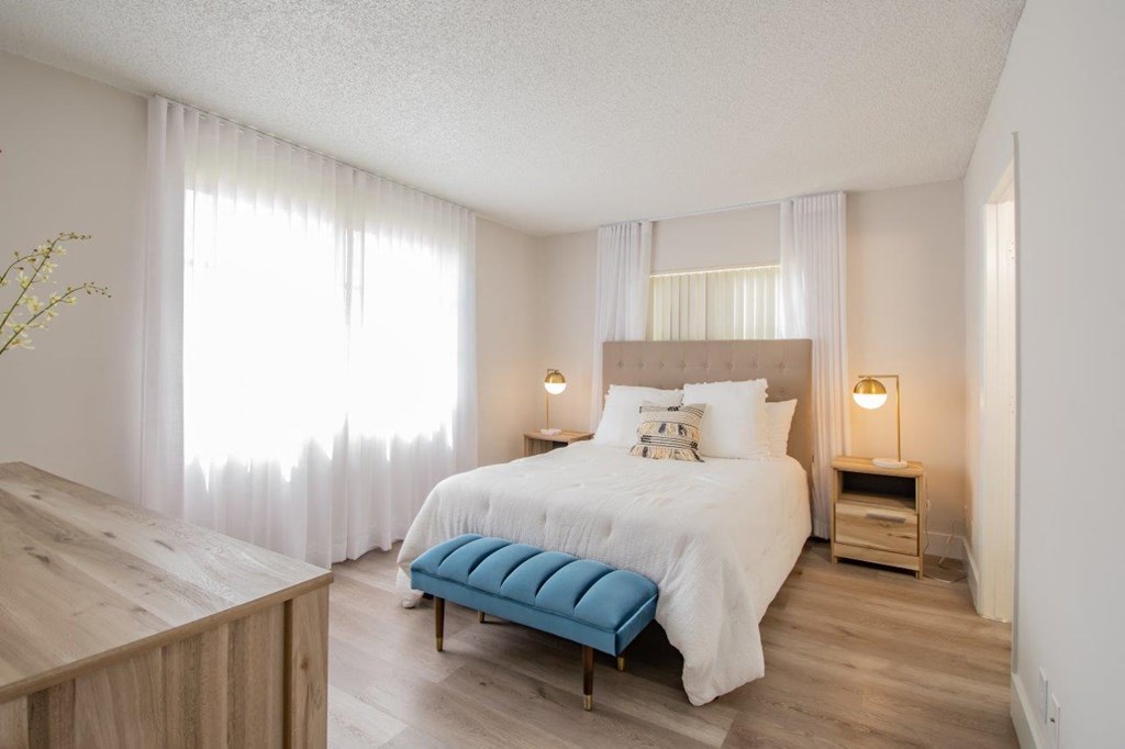 a bedroom with a white bed and a blue bench