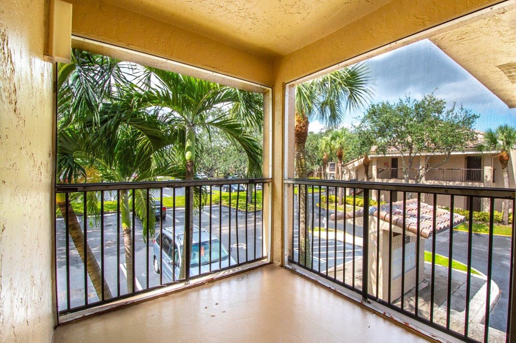 a balcony with a view of a pool and palm trees