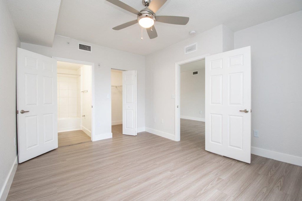 an empty living room with white doors and a ceiling fan
