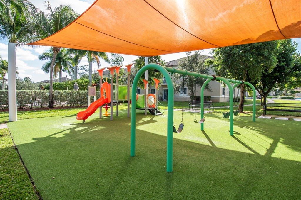 a playground with a swing set under an orange canopy
