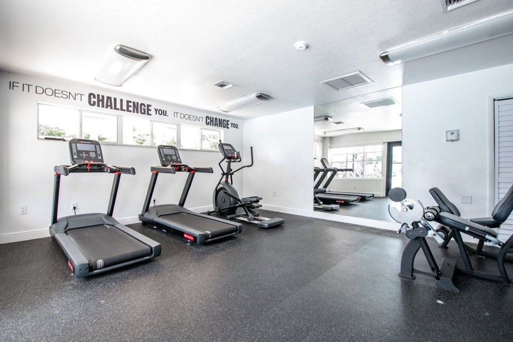A gym with treadmills and a motivational quote on the wall.