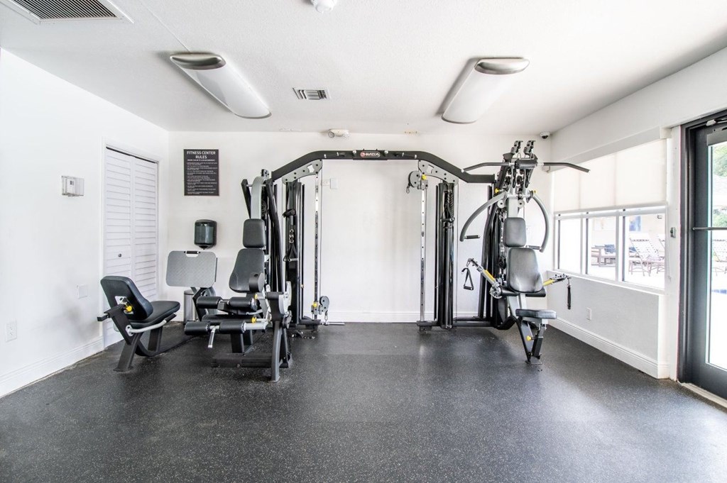 A gym with a variety of equipment including a stationary bike, a rowing machine, and a leg press machine.