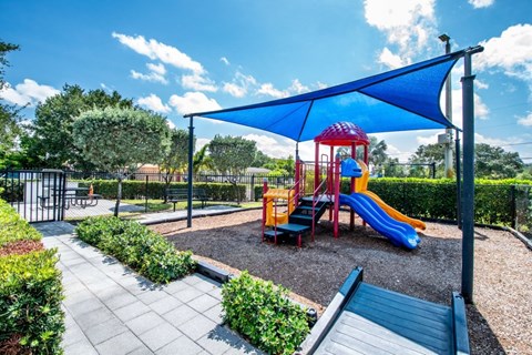 A playground with a red and yellow slide and a blue canopy.