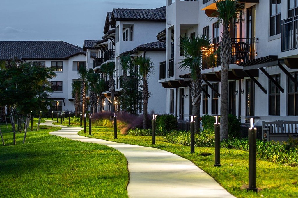 a path through lush green grass next to some apartments