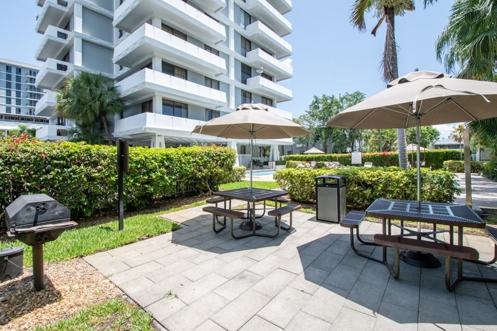 A patio area with tables and umbrellas in front of a building.