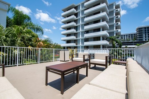 A patio with a table and chairs overlooks a white building.