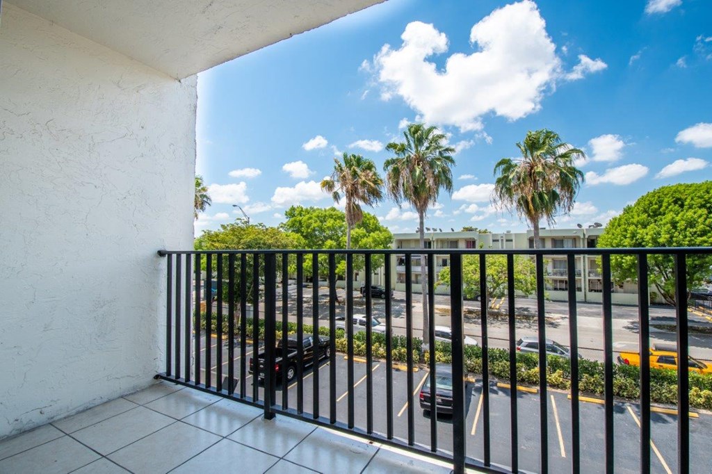 a balcony with a view of a parking lot and palm trees