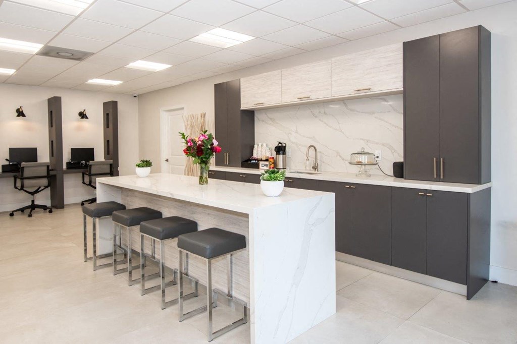 a kitchen with a counter and chairs in a lobby