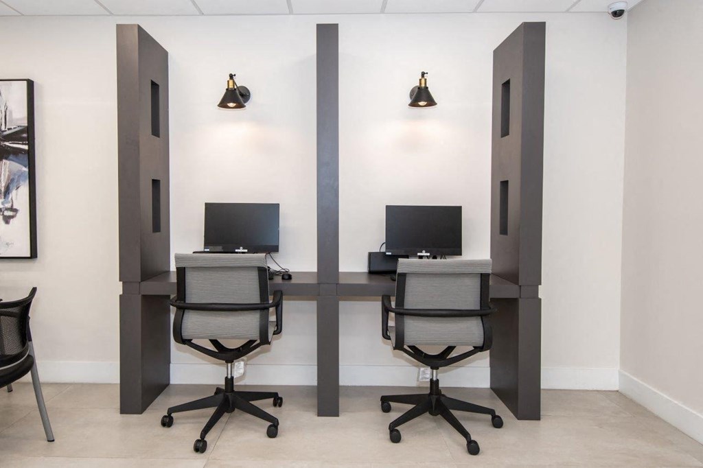 a desk with two monitors in a room with two chairs