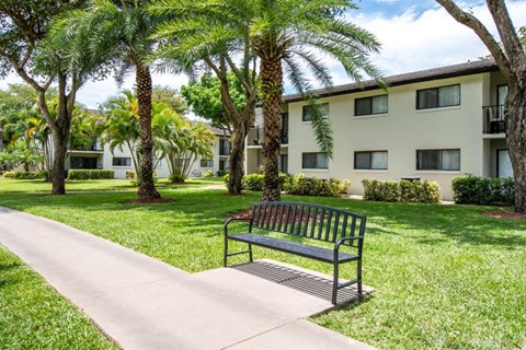 a park bench on a sidewalk in front of an apartment building