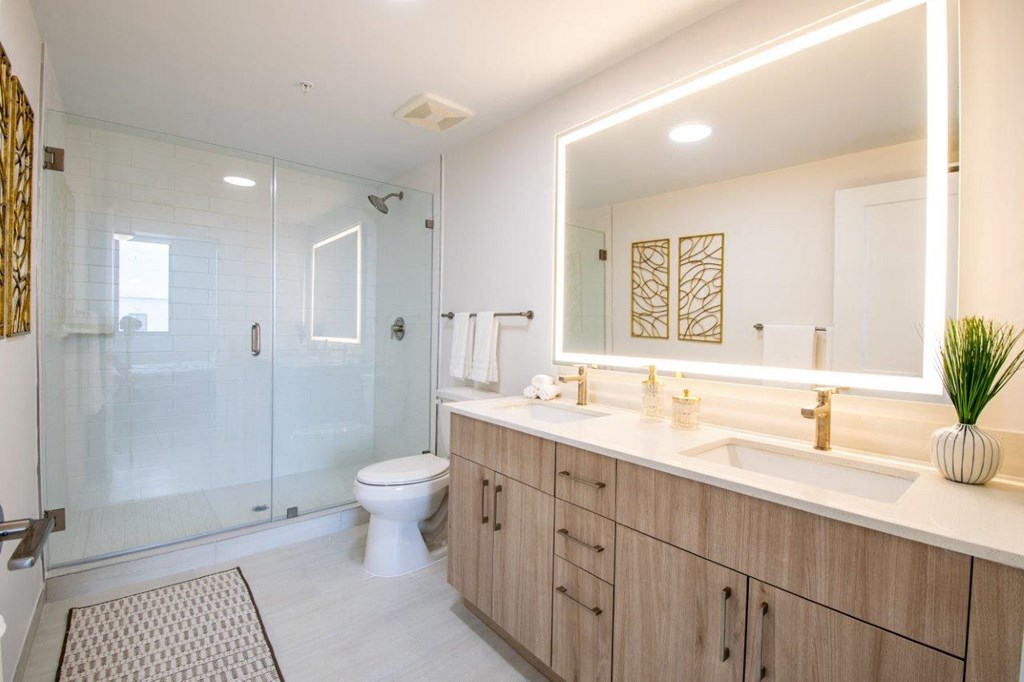 a bathroom with a large mirror and a toilet and a shower