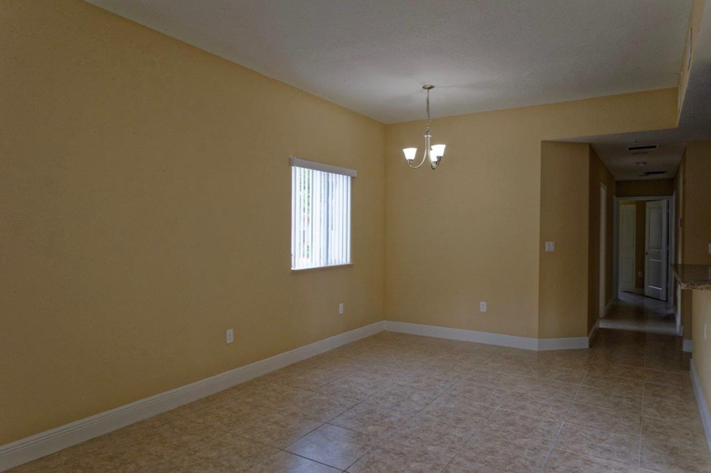 an empty living room with tile flooring and a window