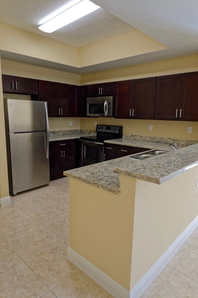 a kitchen with granite counter tops and a stainless steel refrigerator