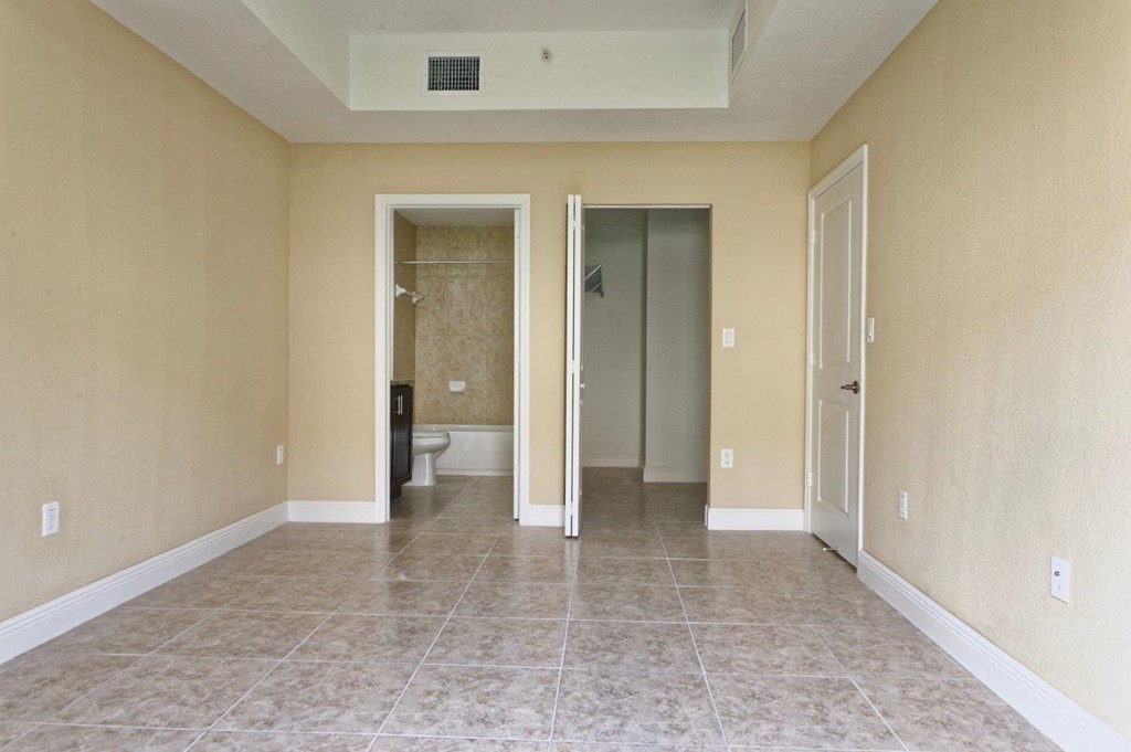 an empty living room with a tiled floor and a bathroom