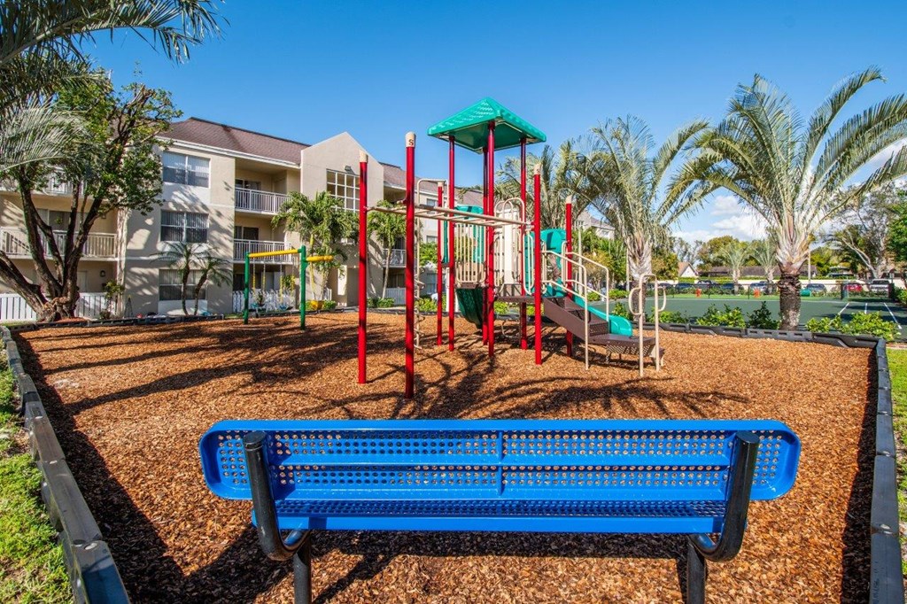 a playground with a blue bench in front of a colorful play set