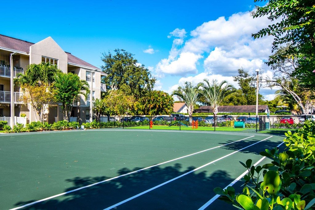 a tennis court with apartments in the background