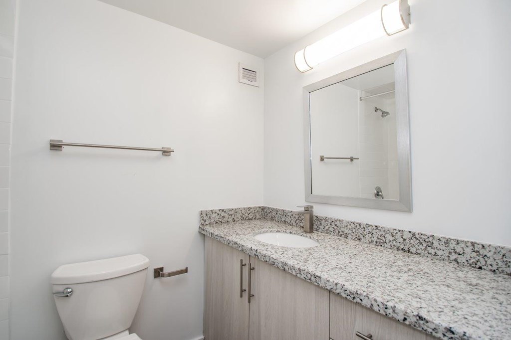 A white bathroom with a toilet, sink, and mirror.
