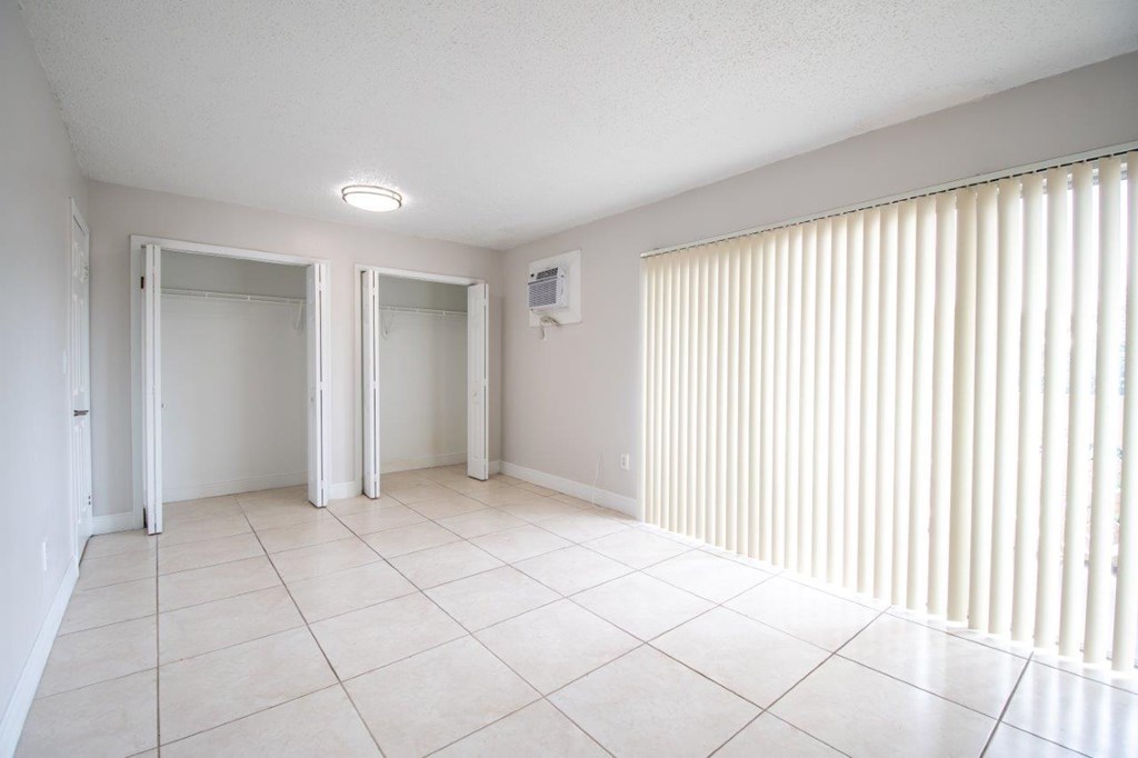 A white tiled room with a window covered in blinds.