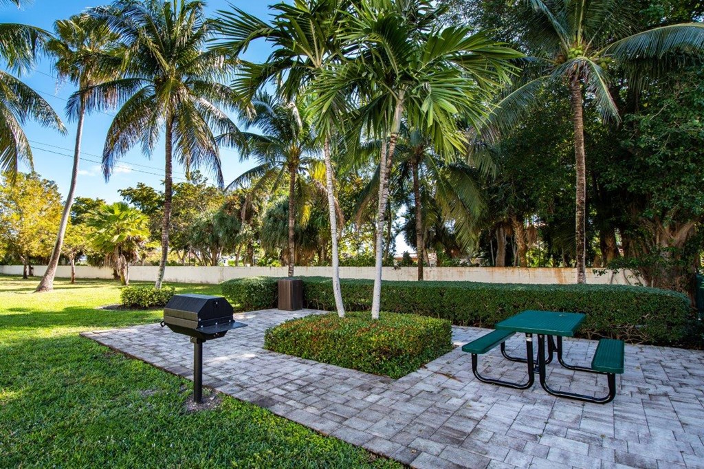 a picnic area with a grill and picnic table in a park