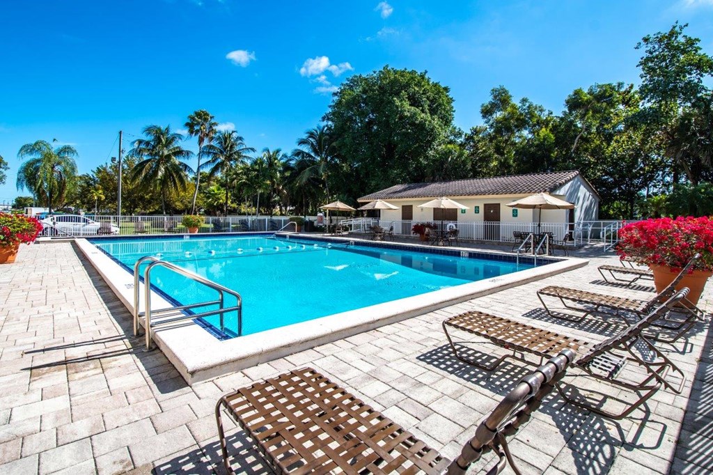 a swimming pool with chairs around it and a house in the background