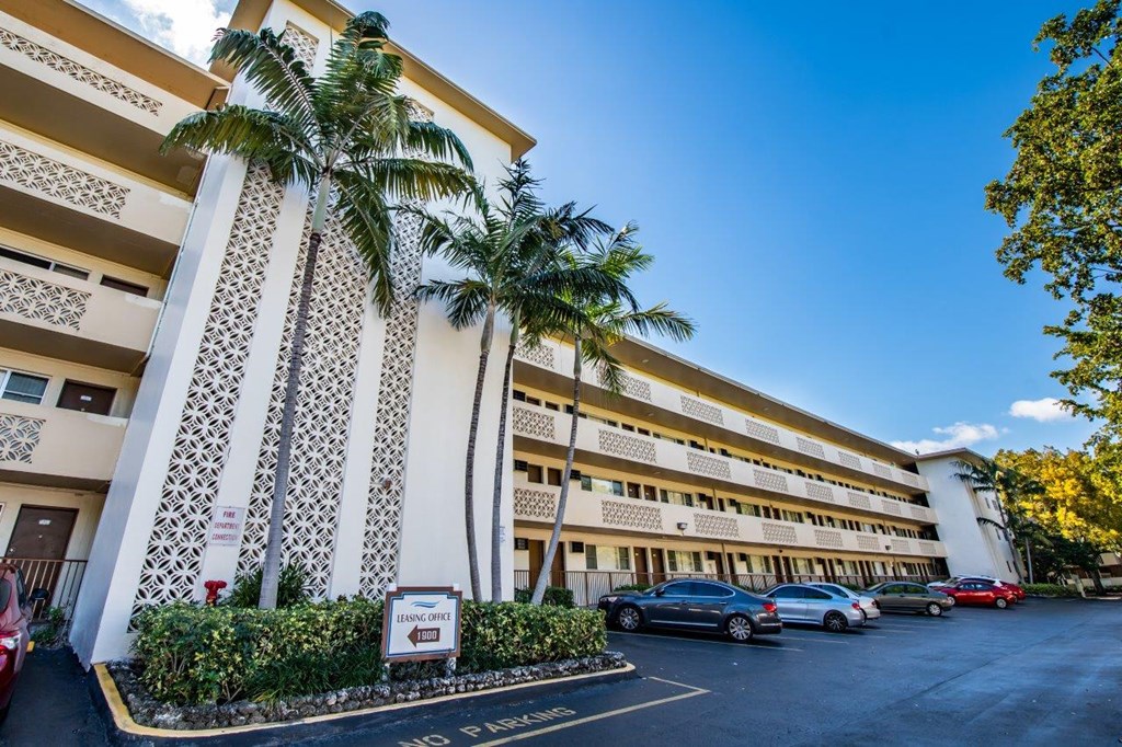 a parking lot in front of a large building with palm trees