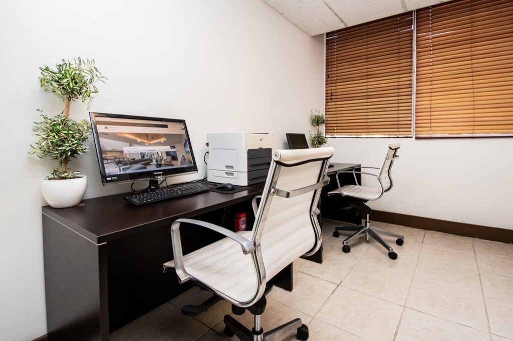 a desk with a computer and a chair in an office