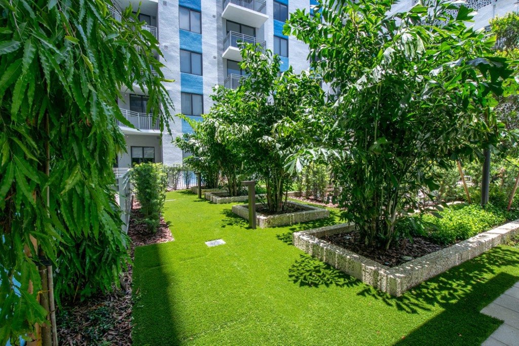 the courtyard of an apartment building with green grass and trees