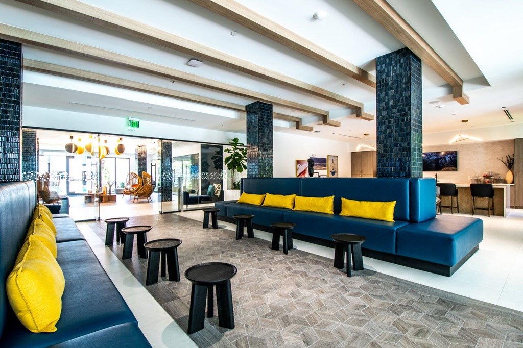 a lobby with blue couches and yellow cushioned stools